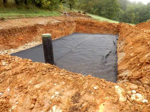 A backhoe digging a trench for a septic tank installation and repair.